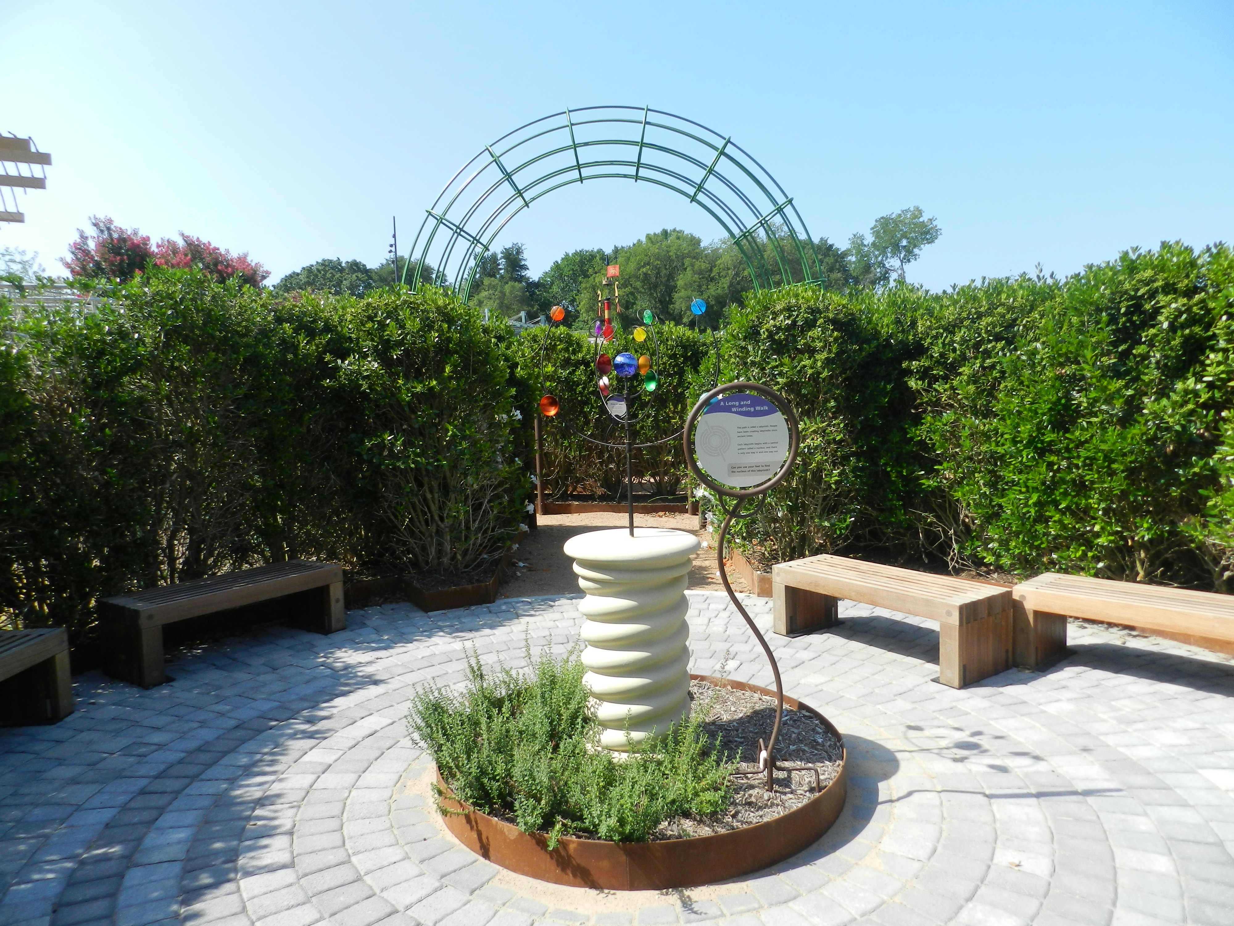 girl in front of weather device in a hedge maze